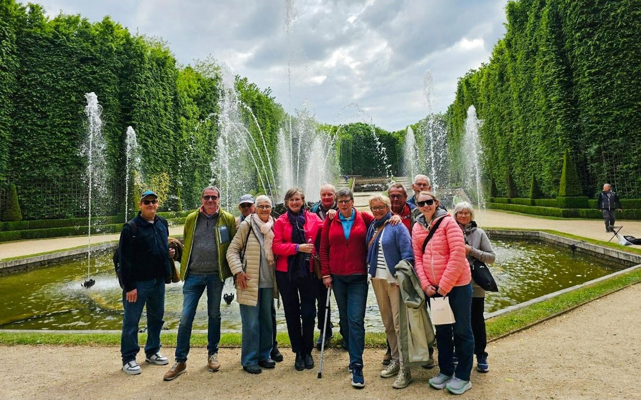 Group enjoying Versailles guided tour by fountains.