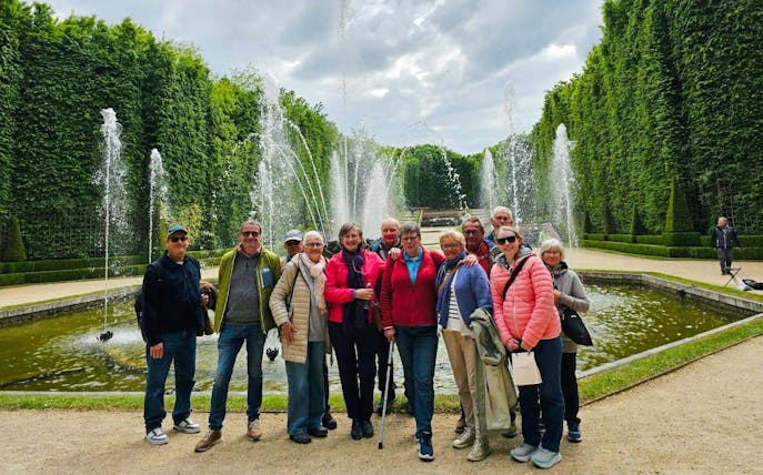 Group enjoying Versailles guided tour by fountains.