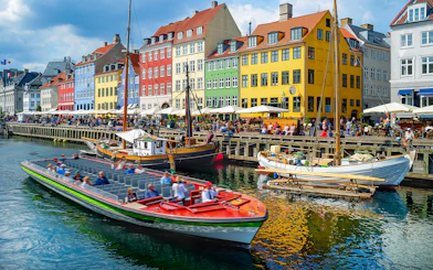 Tour boat cruising by colorful buildings in Nyhavn, Copenhagen.