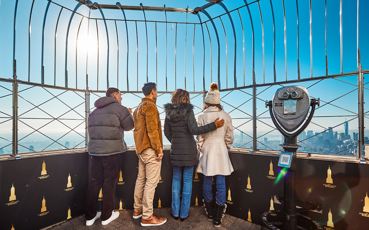 Visitors on the Empire State Building's observation deck enjoying New York City views.