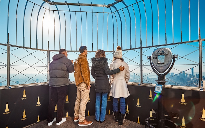 Visitors on the Empire State Building's observation deck enjoying New York City views.