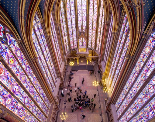 Group tour with guide inside Sainte Chapelle, Paris, showcasing stained glass windows.