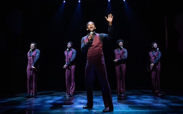 Performers singing on stage in "Ain't Too Proud" musical.