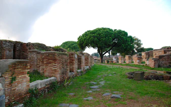 Ostia Antica ruins with ancient brick walls and a tree-lined path, Rome.