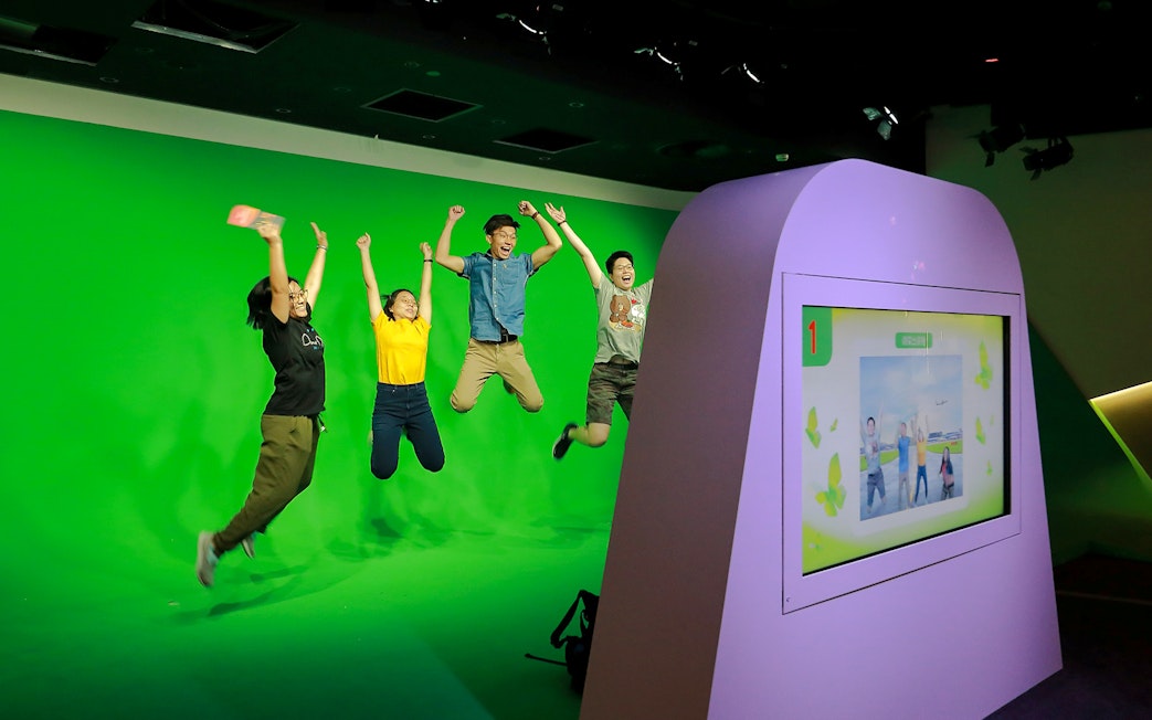 Visitors jumping in front of a green screen at Changi Experience Studio interactive exhibit.