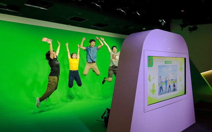 Visitors jumping in front of a green screen at Changi Experience Studio interactive exhibit.