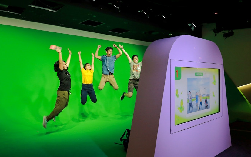 Visitors jumping in front of a green screen at Changi Experience Studio interactive exhibit.