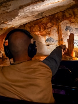 Visitor exploring prehistoric cave art at Grotte Cosquer, France.