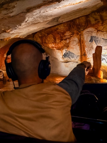 Visitor exploring prehistoric cave art at Grotte Cosquer, France.
