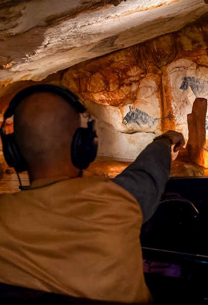 Visitor exploring prehistoric cave art at Grotte Cosquer, France.