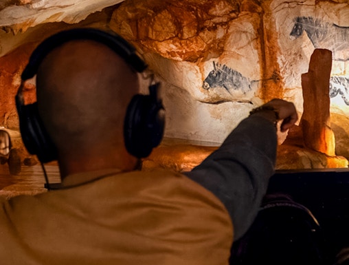 Visitor exploring prehistoric cave art at Grotte Cosquer, France.