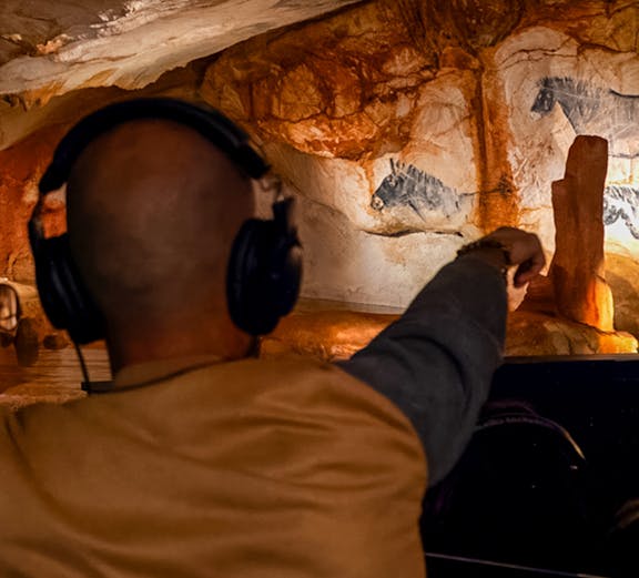 Visitor exploring prehistoric cave art at Grotte Cosquer, France.