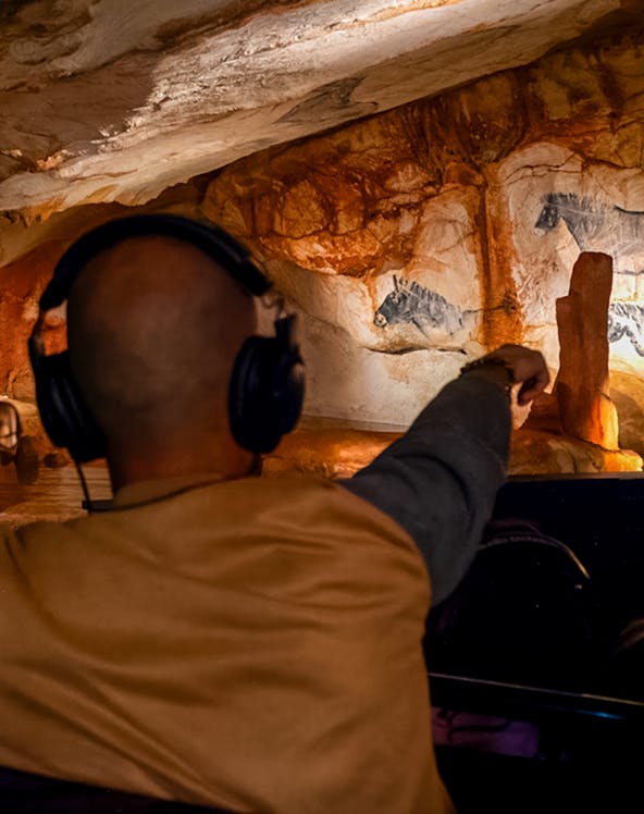 Visitor exploring prehistoric cave art at Grotte Cosquer, France.