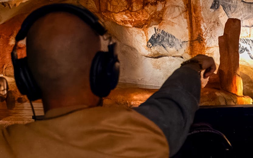Visitor exploring prehistoric cave art at Grotte Cosquer, France.