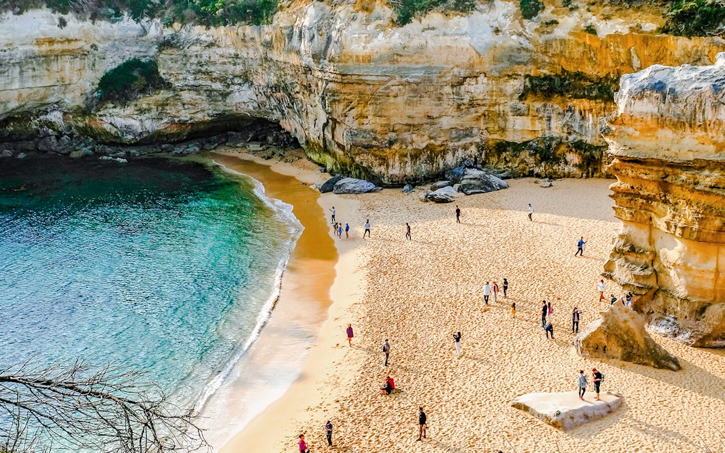Visitors exploring the sandy beach and cliffs on the Great Ocean Road tour from Melbourne.