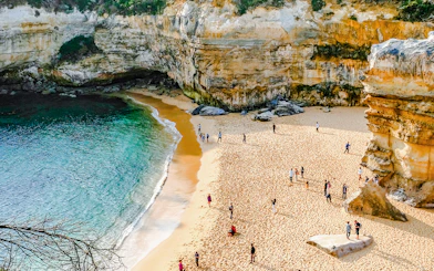 Visitors exploring the sandy beach and cliffs on the Great Ocean Road tour from Melbourne.
