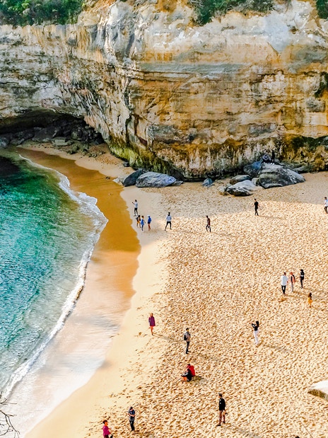 Visitors exploring the sandy beach and cliffs on the Great Ocean Road tour from Melbourne.