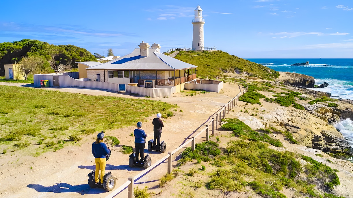 Segway riders on Rottnest Island near a coastal lighthouse.
