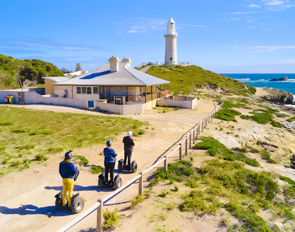 Segway riders on Rottnest Island near a coastal lighthouse.
