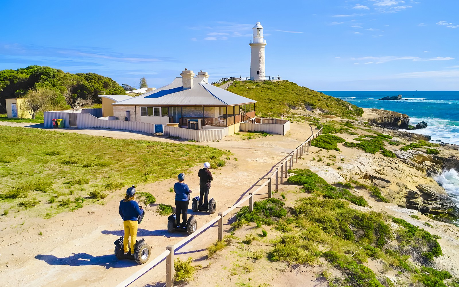 Segway riders on Rottnest Island near a coastal lighthouse.