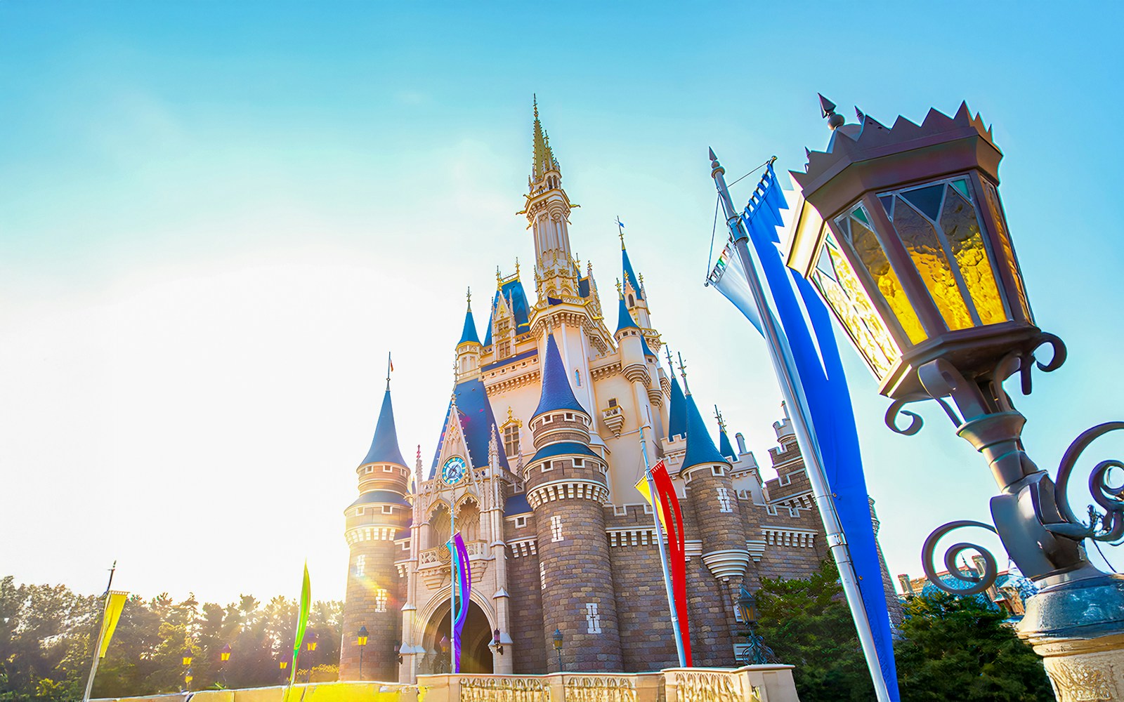 Tokyo Disneyland castle with colorful flags and a vintage lamp in the foreground.