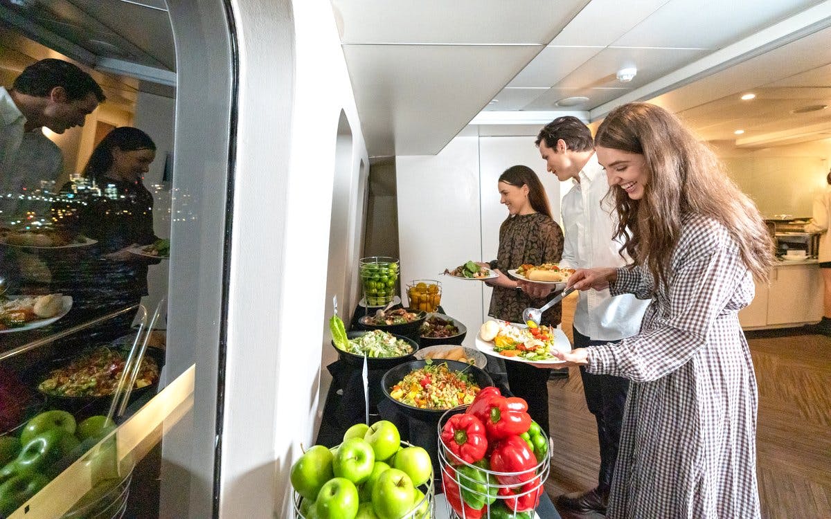 Guests serving from a buffet on a luxury catamaran cruise in Sydney.