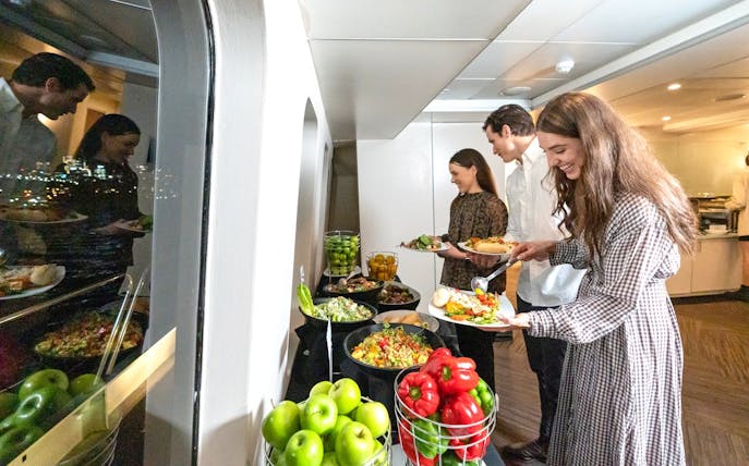 Guests serving from a buffet on a luxury catamaran cruise in Sydney.