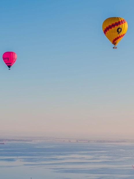 Hot air balloons over Geelong's coastal landscape, Australia, with a ship in the bay.