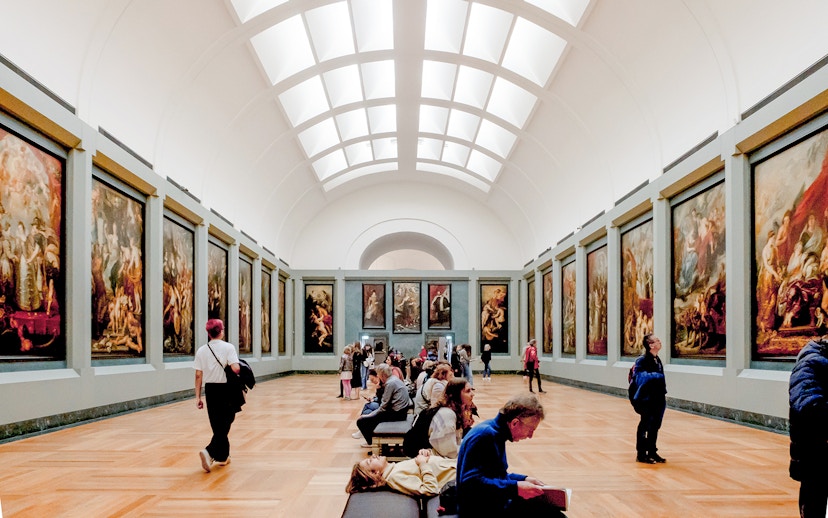 Tourists viewing paintings in a gallery at the Louvre Museum, Paris.