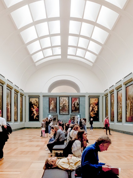 Tourists viewing paintings in a gallery at the Louvre Museum, Paris.