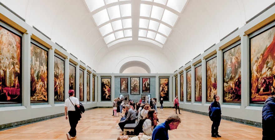 Tourists viewing paintings in a gallery at the Louvre Museum, Paris.