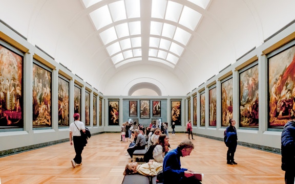 Tourists viewing paintings in a gallery at the Louvre Museum, Paris.