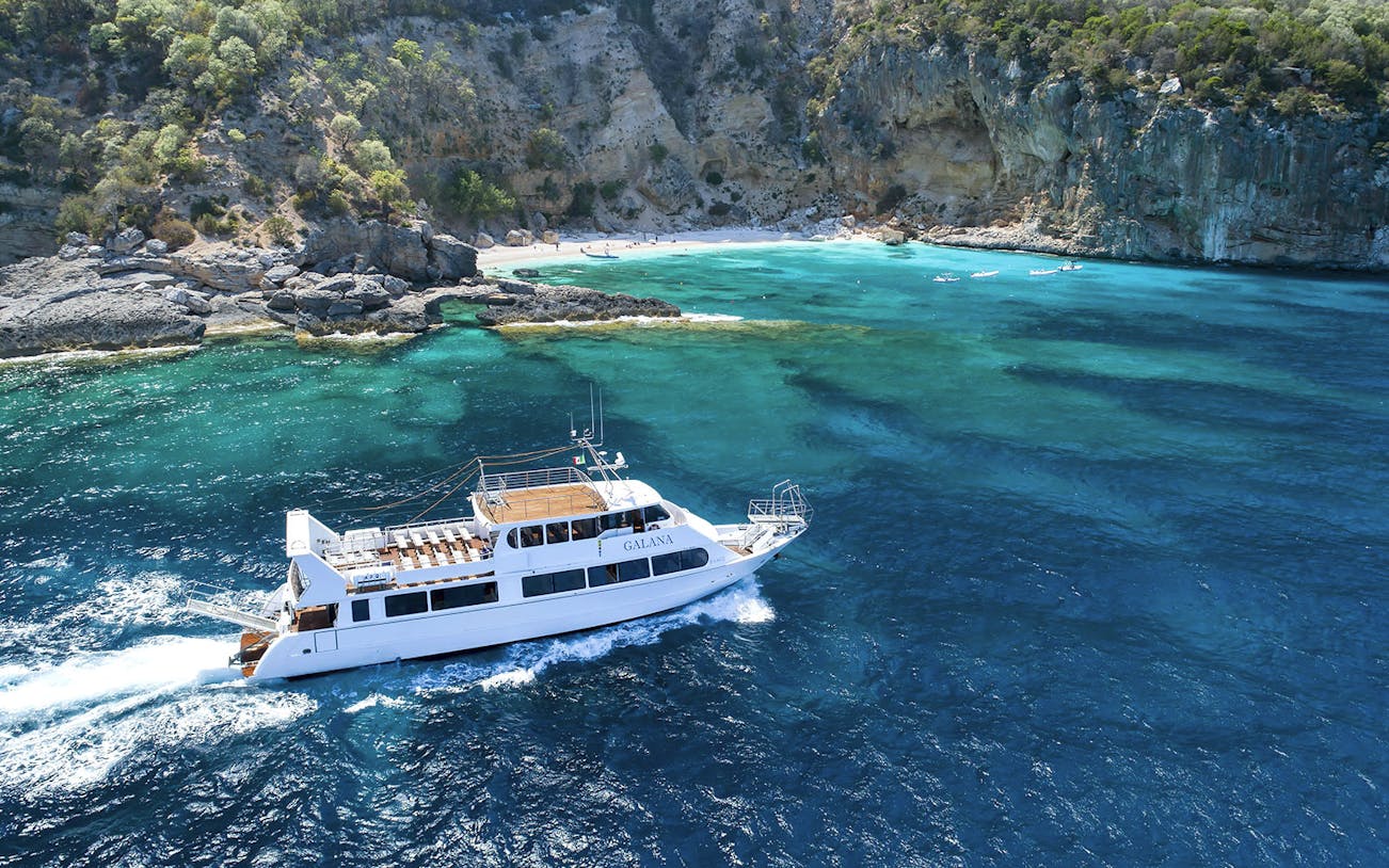 Deluxe boat cruising near La Maddalena Archipelago's rocky coastline and turquoise waters.