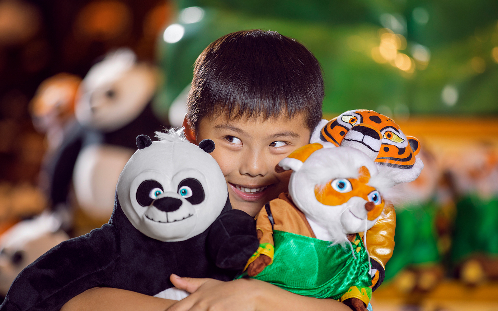 Child holding panda and tiger plush toys 