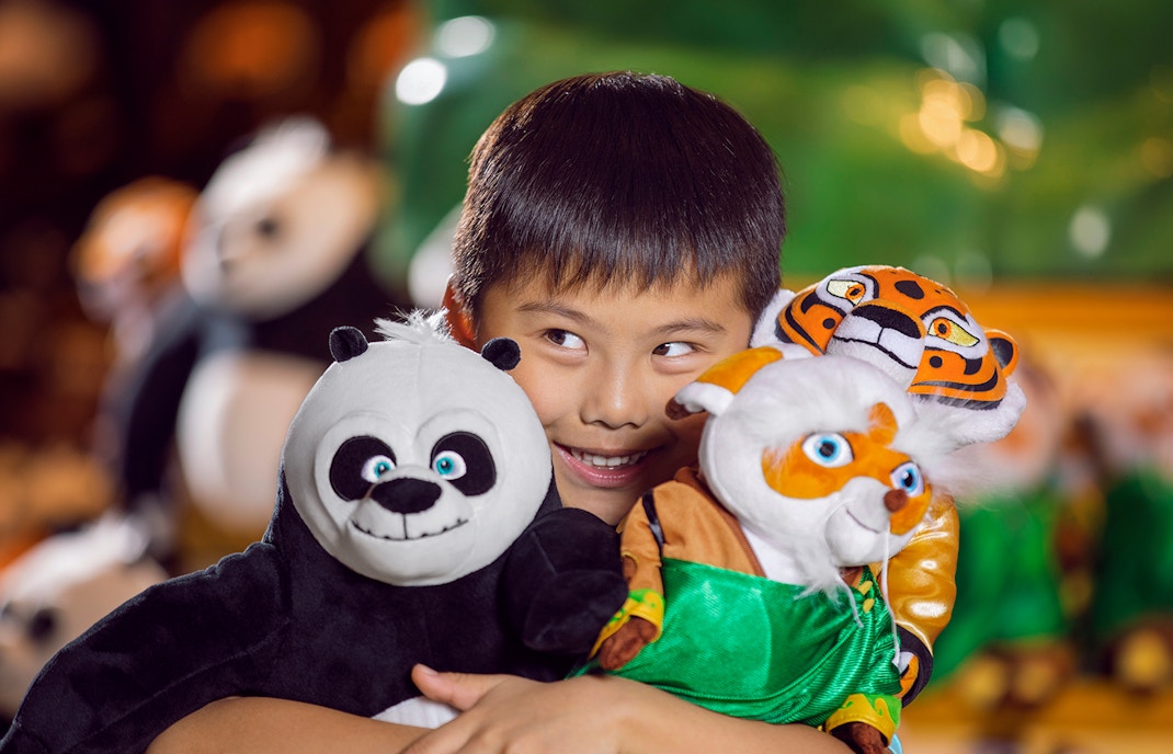 Child holding panda and tiger plush toys