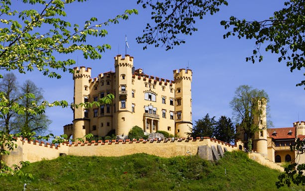 Hohenschwangau Castle surrounded by trees in Bavaria, Germany.