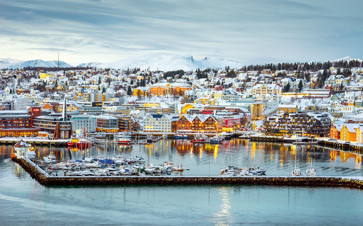 Aerial view of Tromsø harbor with snow-covered buildings and boats.