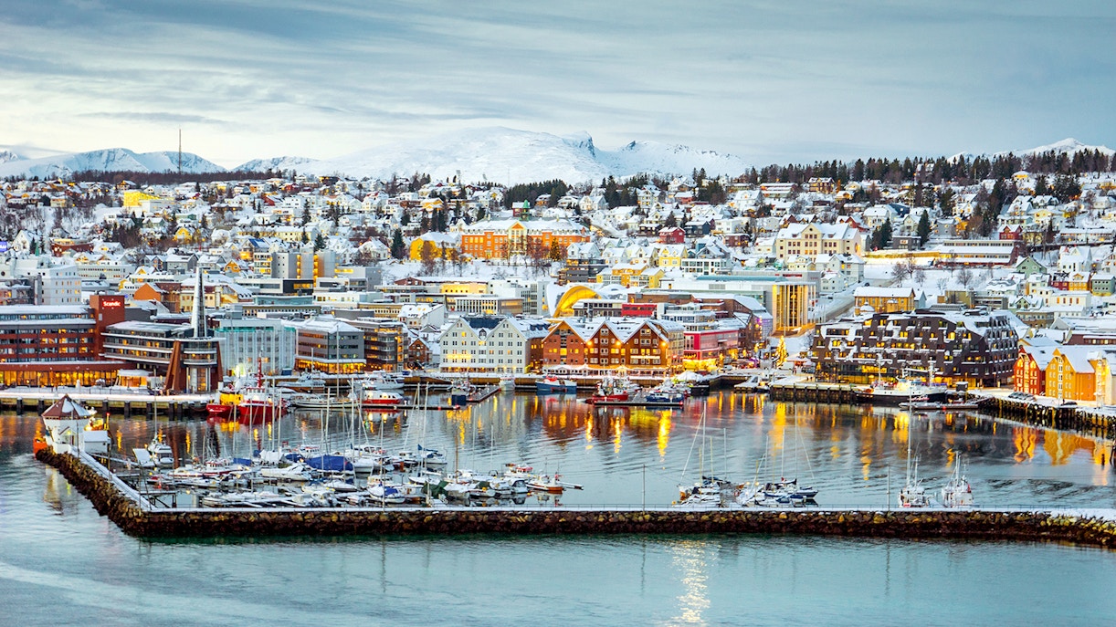 Aerial view of Tromsø harbor with snow-covered buildings and boats.