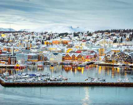 Aerial view of Tromsø harbor with snow-covered buildings and boats.