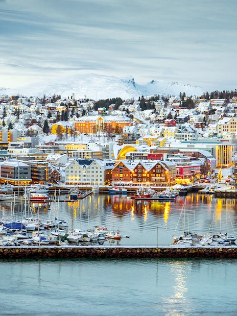 Aerial view of Tromsø harbor with snow-covered buildings and boats.