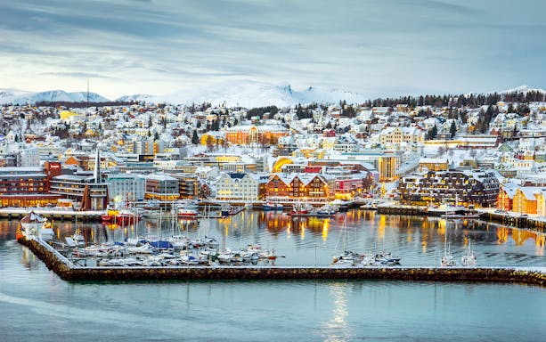 Aerial view of Tromsø harbor with snow-covered buildings and boats.