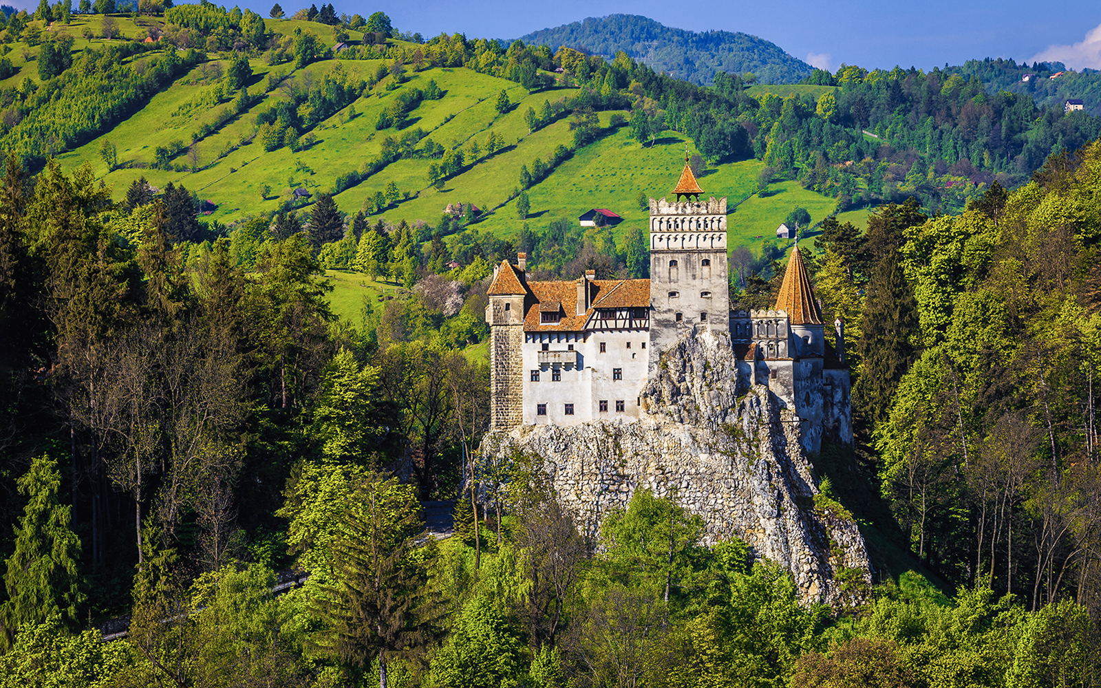 Bran Castle exterior surrounded by lush green hills in Transylvania, Romania.