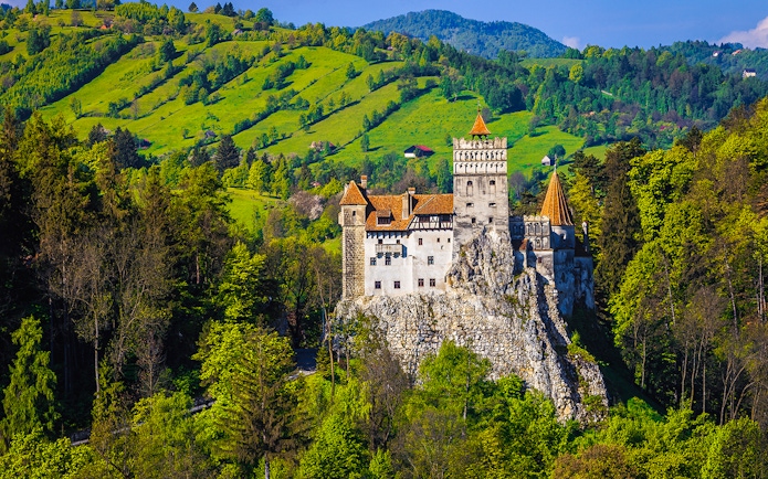 Bran Castle exterior surrounded by lush green hills in Transylvania, Romania.
