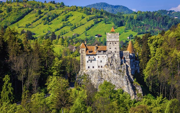 Bran Castle exterior surrounded by lush green hills in Transylvania, Romania.