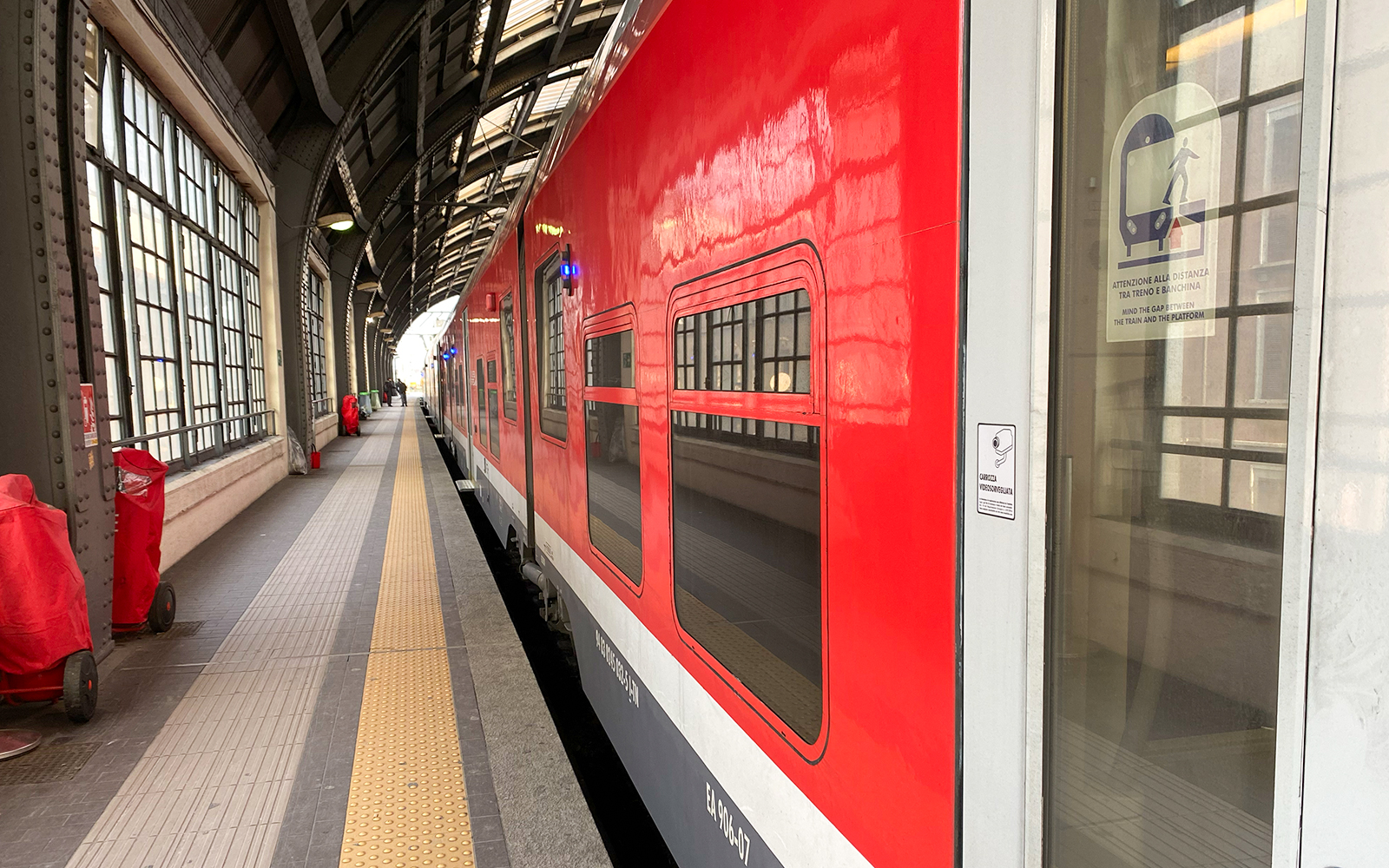 Red train at Milan Central Station platform for Malpensa Airport route.