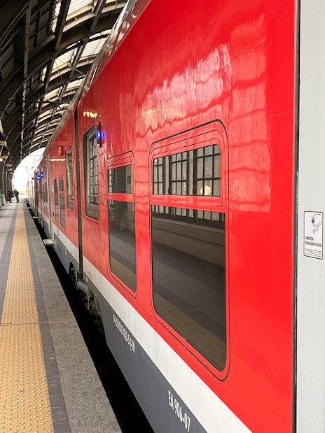Red train at Milan Central Station platform for Malpensa Airport route.