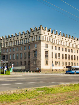 Historic building in Nowa Huta, Krakow, with a blue bus passing by.