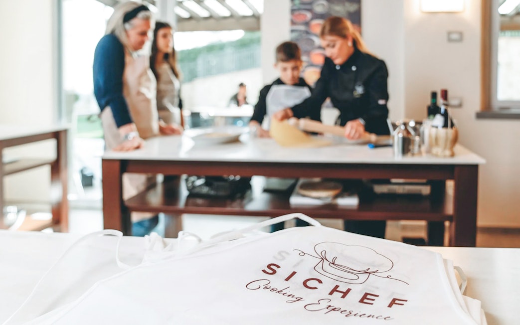 Cooking class participants making fresh pasta with chef guidance.