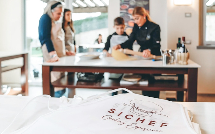 Cooking class participants making fresh pasta with chef guidance.