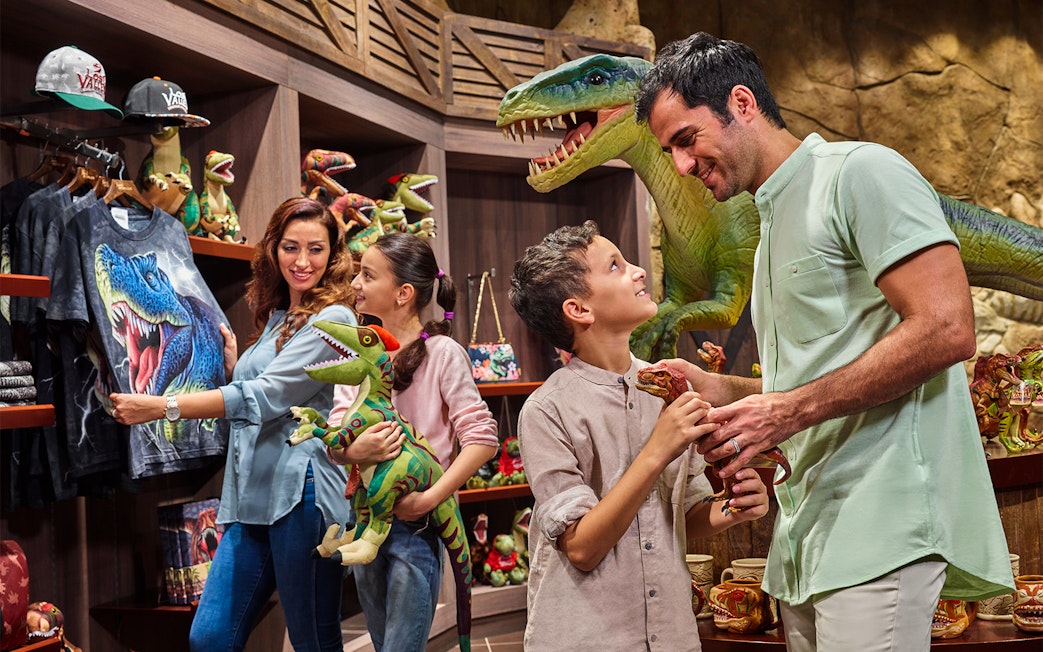 Family shopping for dinosaur toys at IMG Worlds of Adventure gift shop.